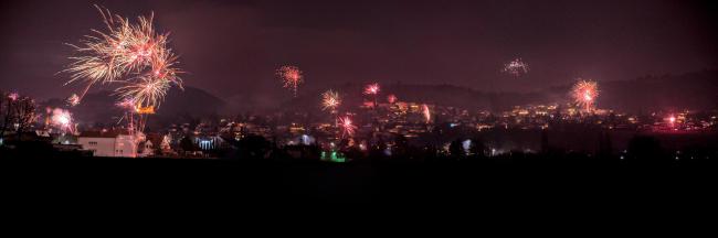 Panorama der Bergstraße bei Nacht. Der Vordergrund ist quasi schwarz. Im Hintergrund ist jede Menge Feuerwerk über der Bergstraße zu sehen die dadurch in einen roten Lichtschein getaucht ist.