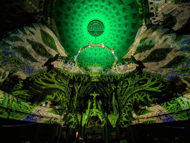 Blick nach oben auf die Visuals. Gerade ist alles in Grün, schwarz und beige Visuals getaucht die wie Arme oder kahle Äste in einem winterlichen Wald aussehen.