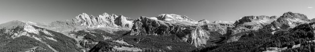 Sehr großes Panorama in Schwarz-Weiß. Es zeigt die Aussicht über viele Berge auf der nördlichen Seite des Val-Gardena. Von Links nach Rechts die Seceda, die Geislergruppe, das Langtal und das Cirjoch und vermutlich noch einiges mehr.