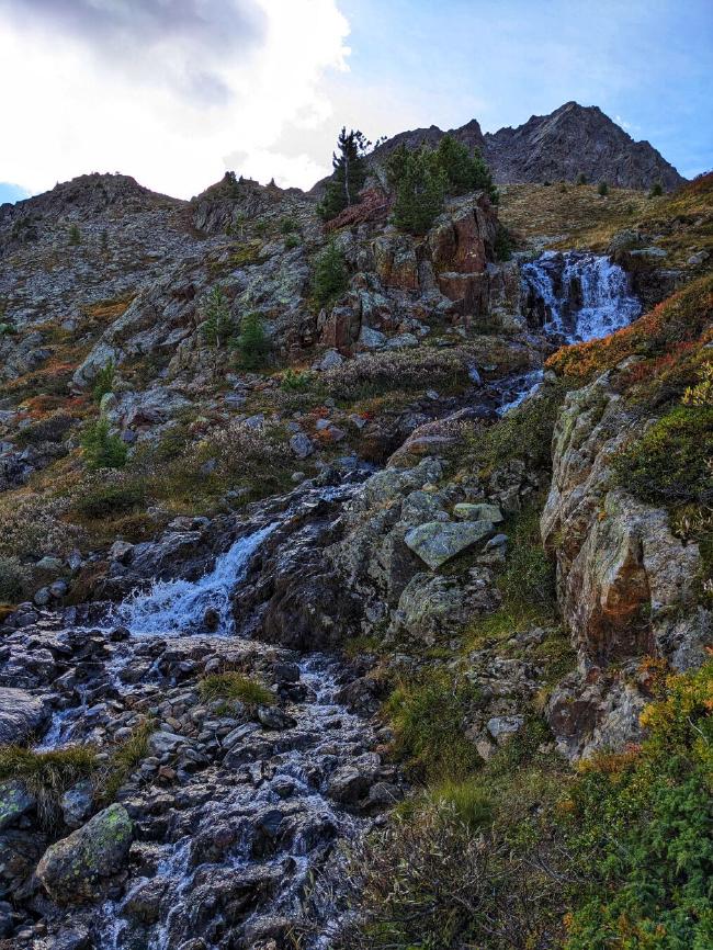 Ein mehrstufiger Wasserfall zwischen bunten Sträuchern
