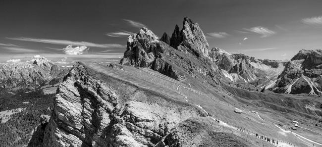 Schwarz-Weiß Panorama. Man sieht den Blick über eindrucksvolle zerklüftete Abbruchkante der Seceda und dahinter die Geislergruppe.